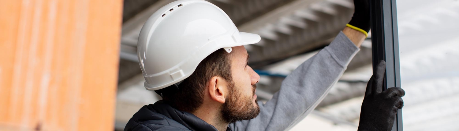 Side view of a construction worker installing a glass window or door